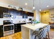 Thumbnail 4 of 29 - Eat in kitchen with black cabinetry, sleek stainless steel appliances, and pendant lights.