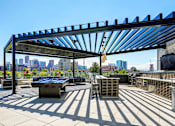 Thumbnail 17 of 29 - Sky deck at Westend Apartments featuring a full grilling station, billiards table, and island seating covered by a pergola.
