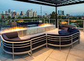 Thumbnail 21 of 29 - The stylish rooftop features a large outdoor fireplace, comfortable seating, and a pergola all looking out onto stunning skyline views.