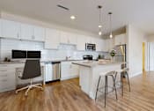 Thumbnail 1 of 29 - Spacious modern kitchen with white cabinetry, stainless steel appliances, and pendant lighting above the island. Kitchen opens up into separate dining area.