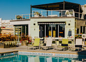 Thumbnail 18 of 29 - a swimming pool with chairs next to a poolside building