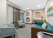Thumbnail 20 of 29 - A living room with a blue couch and a patterned chair.