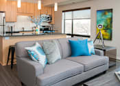 Thumbnail 3 of 18 - a living room with a couch in front of a kitchen