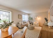 Thumbnail 2 of 29 - A living room with a couch, chair, and potted plant.