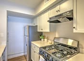 Thumbnail 17 of 29 - A modern kitchen with a stainless steel gas stove and white cabinets.