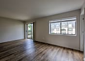 Thumbnail 21 of 29 - A room with wooden floors and a window showing a view of buildings outside.