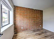 Thumbnail 24 of 29 - A room with a red brick wall and wooden flooring.