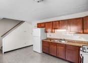 Thumbnail 7 of 12 - A kitchen with brown cabinets and a white refrigerator.