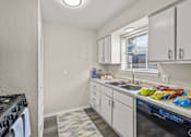 Thumbnail 19 of 32 - A kitchen with white cabinets and a black stove top oven. at La Bella Apartments, Fort Worth, TX