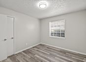 Thumbnail 27 of 32 - A room with a white door, a window with blinds, and a wooden floor. at La Bella Apartments, Fort Worth, Texas