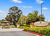 Thumbnail 20 of 57 - a villa with a driveway and a sign that says Peninsula Pines Apartments