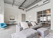 Thumbnail 80 of 131 - A modern living room with a grey couch, a blue chair, and a white desk.
