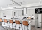 Thumbnail 68 of 131 - A modern kitchen with a bar area and chairs.