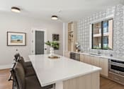 Thumbnail 4 of 46 - A modern kitchen with a large island and a dining table.