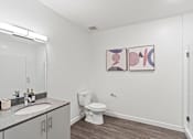 Thumbnail 93 of 131 - A bathroom with a toilet, sink, and two framed pictures on the wall.