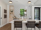 Thumbnail 3 of 46 - A kitchen with a white countertop and brown chairs.