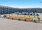 Thumbnail 26 of 74 - A parking lot in front of apartment buildings with a sign that says Bark Park. at Red Rock Apartments, South Dakota