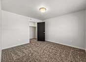 Thumbnail 64 of 74 - an empty living room with carpet and a door to a closet at Red Rock Apartments, South Dakota 57702
