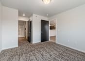 Thumbnail 65 of 74 - a living room with carpet and white walls and a black door at Red Rock Apartments, Rapid City, SD, 57702