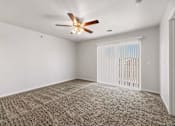 Thumbnail 62 of 74 - an empty living room with a ceiling fan and a window at Red Rock Apartments, Rapid City, SD