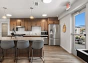 Thumbnail 39 of 74 - a kitchen with stainless steel appliances and a bar with four chairs at Red Rock Apartments, Rapid City