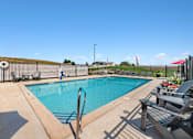 Thumbnail 33 of 74 - a swimming pool with chairs and a fence around it at Red Rock Apartments, South Dakota 57702