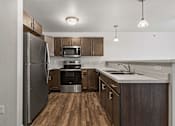Thumbnail 54 of 74 - an empty kitchen with stainless steel appliances and wooden cabinets at Red Rock Apartments, Rapid City