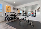 Thumbnail 46 of 74 - a home gym with weights and mirrors and a large mirror on the wall at Red Rock Apartments, South Dakota