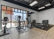 Thumbnail 19 of 35 - a gym with weights and other exercise equipment and a large window at City View St. George Apartments, St George, UT