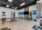 Thumbnail 18 of 35 - a gym with weights and exercise equipment and a wall with a colorful painting at City View St. George Apartments, St George