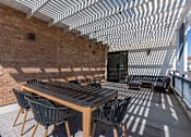 Thumbnail 21 of 35 - a patio with a wooden table and chairs and a brick wall at City View St. George Apartments, Utah