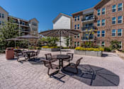 Thumbnail 5 of 35 - a patio with tables and umbrellas in front of an apartment building at City View St. George Apartments, St George, UT