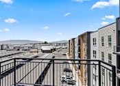 Thumbnail 66 of 144 - A view from a balcony overlooking a parking lot and a row of buildings.