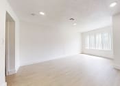 Thumbnail 30 of 34 - an empty living room and dining room with white walls and wood floors