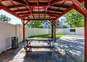Thumbnail 21 of 45 - A wooden picnic table is under a red and white canopy.