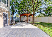 Thumbnail 23 of 45 - A wooden gazebo is situated in a backyard with a paved walkway leading to it.
