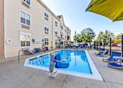 Thumbnail 22 of 45 - A swimming pool surrounded by lounge chairs and umbrellas in a residential area.