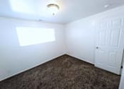 Thumbnail 13 of 14 - A room with a carpeted floor, a white door, and a window with blinds.