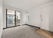 Thumbnail 77 of 92 - A room with a carpeted floor, a white door, and a sliding glass door leading to a balcony. at AVIA Lofts on Parkway Apartments, Vancouver, Washington