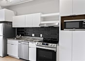 Thumbnail 19 of 55 - A modern kitchen with white cabinets and black appliances.