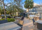 Thumbnail 45 of 61 - a patio with tables and chairs and a grill at AVIA Lofts on Liberty Ridge, Jacksonville, FL, 32256