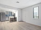 Thumbnail 51 of 61 - the living room and kitchen of an apartment with a crib and a refrigerator at AVIA Lofts on Liberty Ridge, Florida, 32256