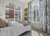 Thumbnail 79 of 83 - a bedroom with a bed and a window with blue and white curtains at 200 City View, Provo, Utah