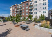 Thumbnail 18 of 83 - an outdoor patio with benches and trees in front of an apartment building at 200 City View, Provo, Utah