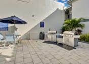 Thumbnail 6 of 41 - a patio with a grill and a table with chairs and an umbrella