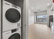 Thumbnail 27 of 55 - A modern laundry room with a washer and dryer stacked on top of each other.