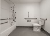 Thumbnail 91 of 92 - A white toilet in a bathroom with a shower head and hand held shower at AVIA Lofts on Parkway Apartments, Vancouver, WA, 98662