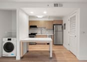 Thumbnail 84 of 92 - A modern kitchen with a white table and wooden cabinets at AVIA Lofts on Parkway Apartments, Washington, 98662