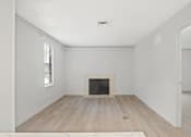 Thumbnail 53 of 61 - an empty living room with a fireplace and wooden floors at AVIA Lofts on Liberty Ridge, Florida