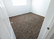 Thumbnail 5 of 14 - A carpeted room with a door and a window.